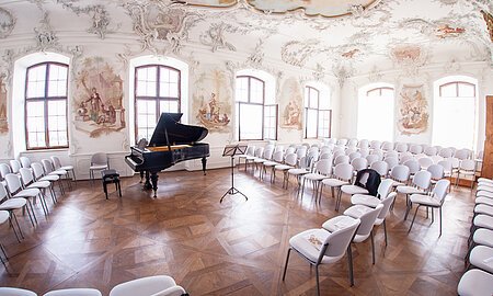 Konzertsaal Ein Blick in den Rokokofestsaal von Schloss Leitheim, vorbereitet für ein Konzert mit Flügel und Bestuhlung.