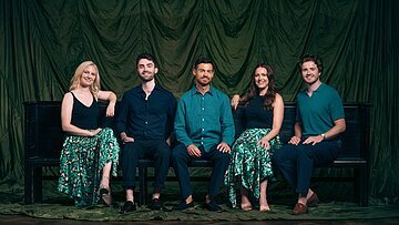 Die fünf Sänger von Apollo 5 auf einer Bank.