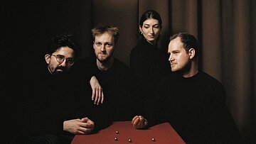 Sie sehen das Quatuor Agate in der aktuellen Besetzung an einem Tisch sitzen